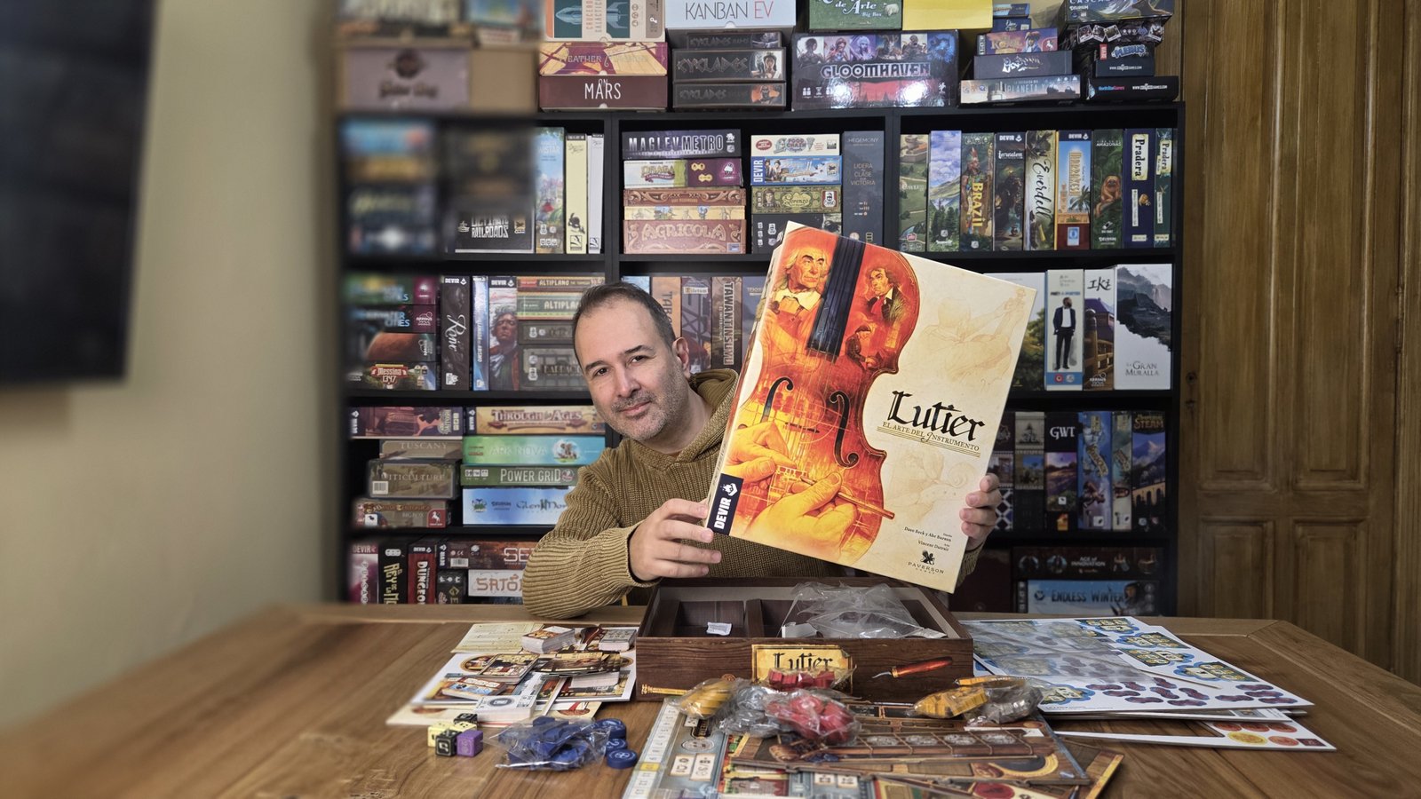 Fernando, Chamán, fundador de ChamanGeek, mostrando el juego de mesa Lutier frente a su colección personal